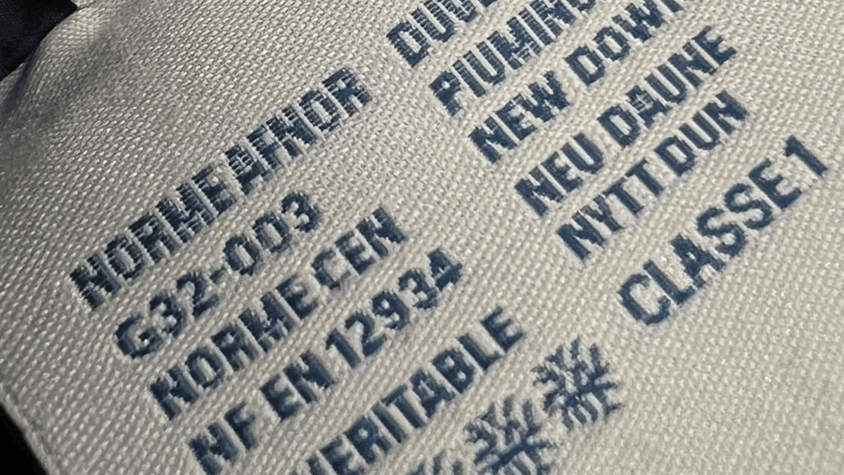 Logo Moncler en gros plan sur une doudoune marine, en illustration des questions fréquentes sur la marque