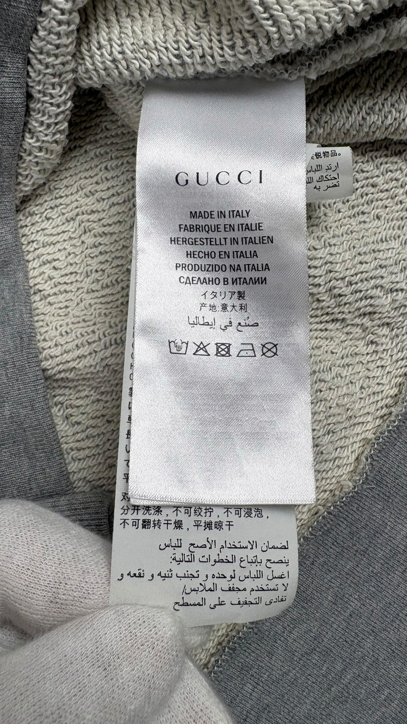 Étiquette intérieure de composition et d'entretien du crewneck Gucci avec mention Made in Italy et symboles de lavage