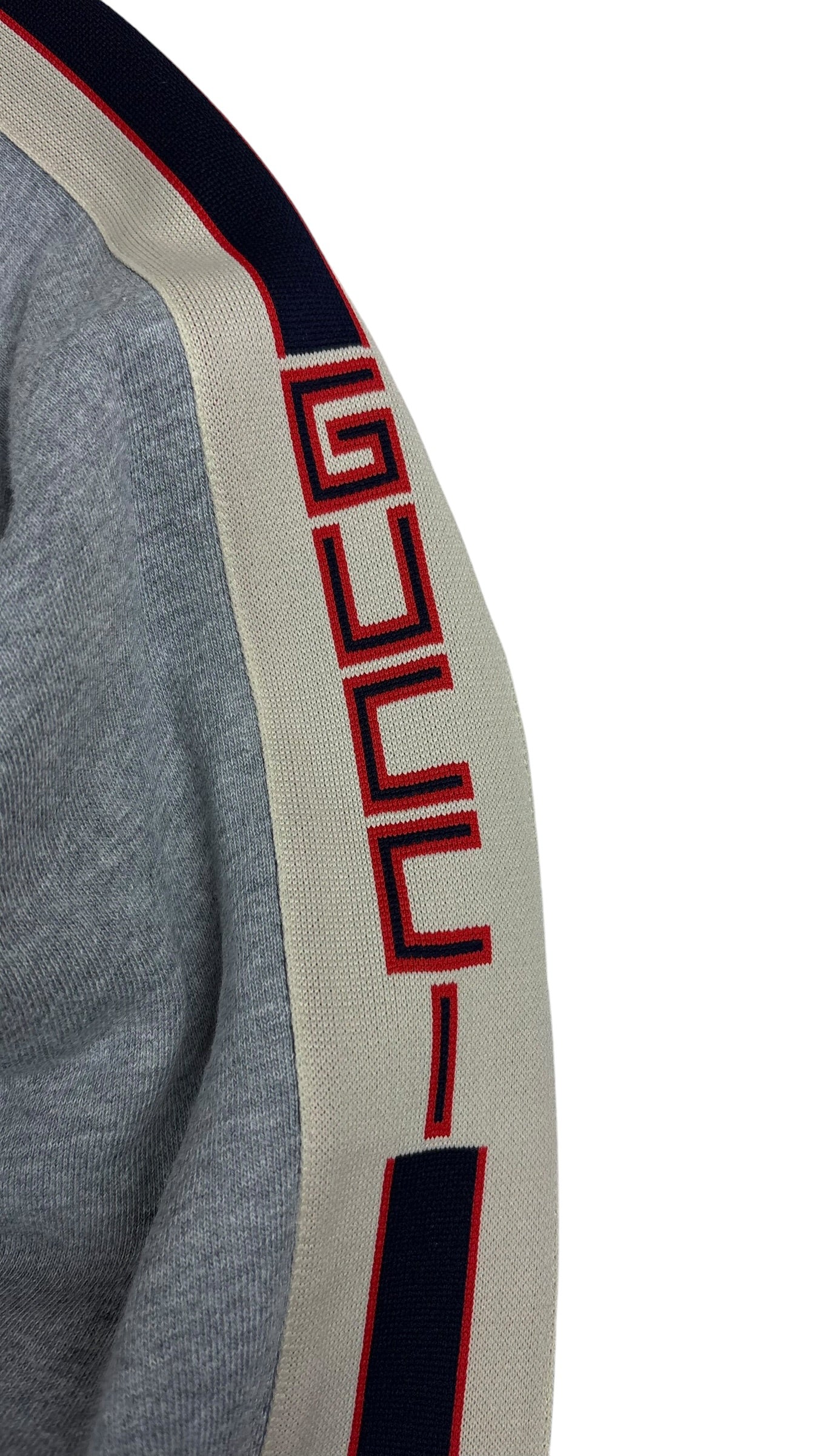 Détail de la manche du crewneck Gucci montrant la bande Web bleu marine, crème et rouge avec l'inscription GUCCI