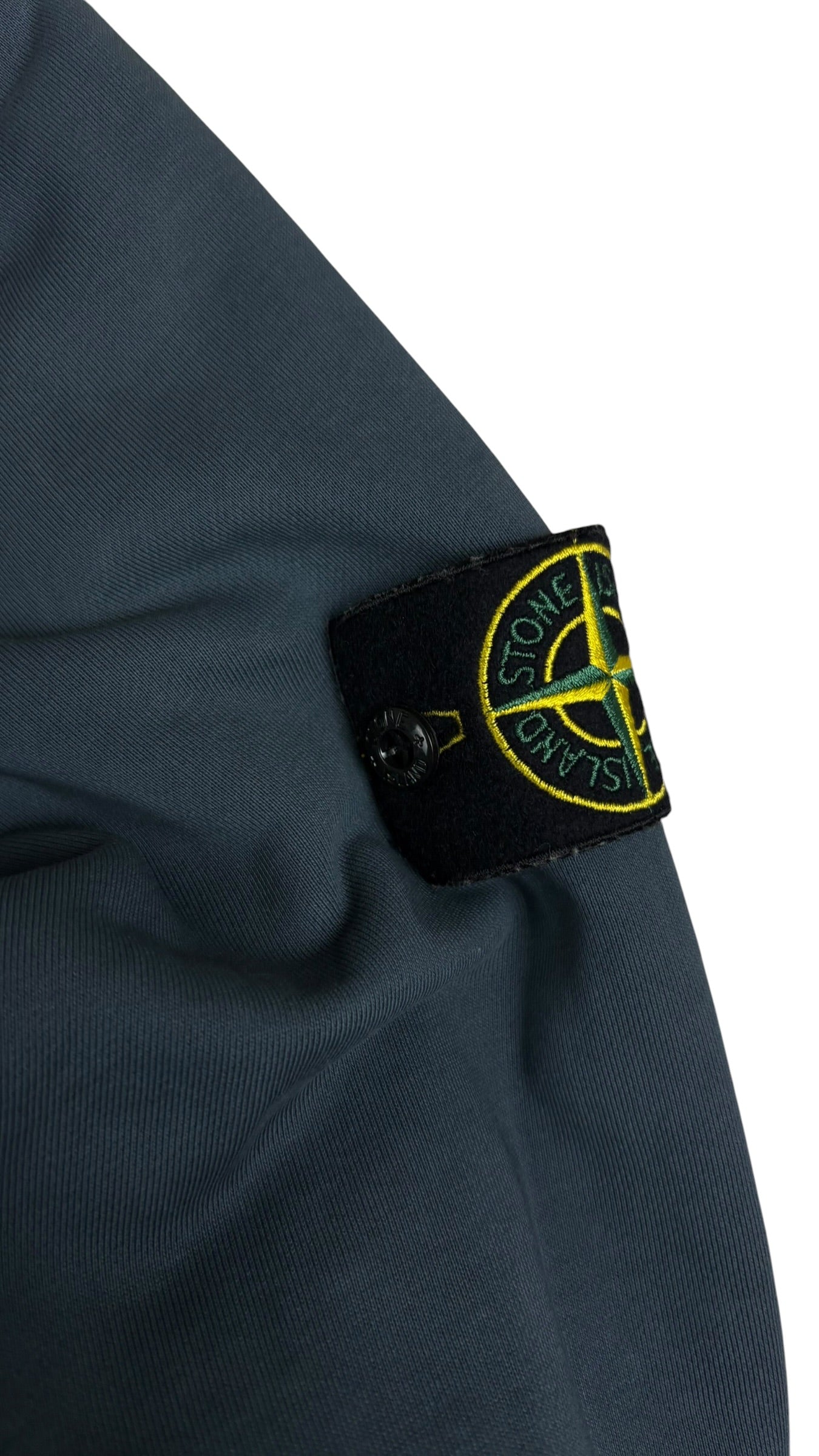 Gros plan sur le badge boussole Stone Island amovible cousu sur la manche du gilet marine