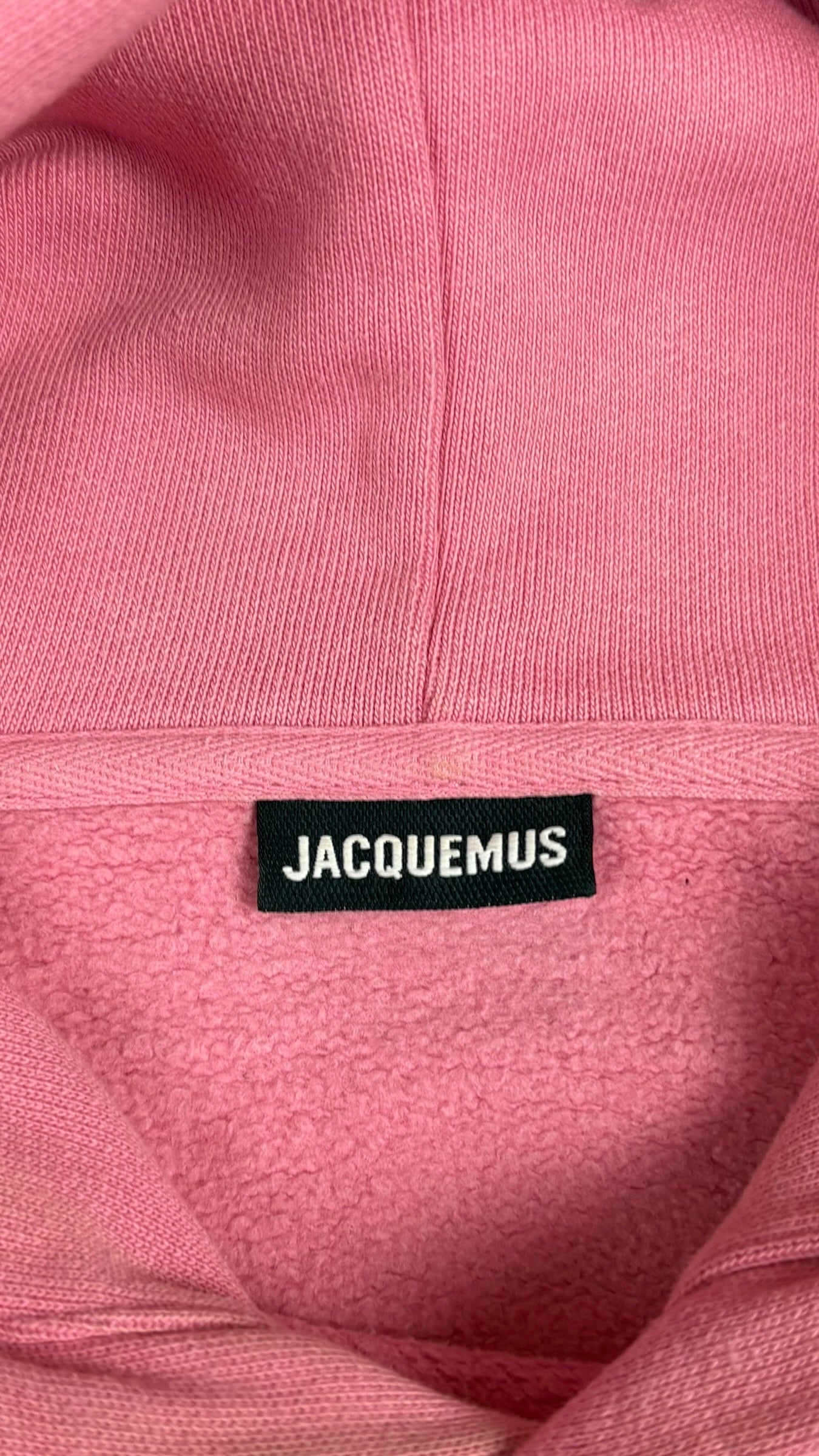 Étiquette de marque Jacquemus noire cousue à l'intérieur du col du hoodie rose