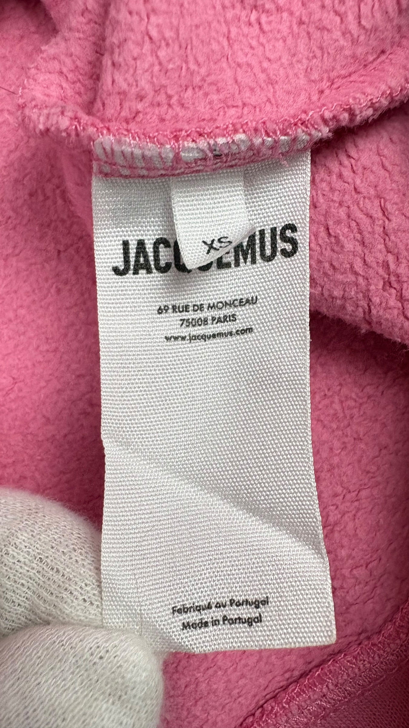 Étiquette intérieure Jacquemus indiquant la taille XS, fabriqué au Portugal, du hoodie rose
