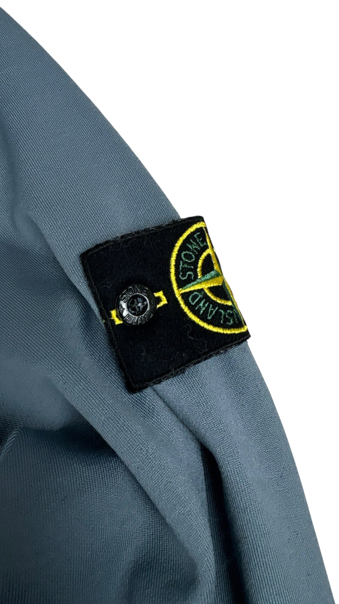 Gros plan du badge boussole Stone Island sur la manche gauche du hoodie bleu marine