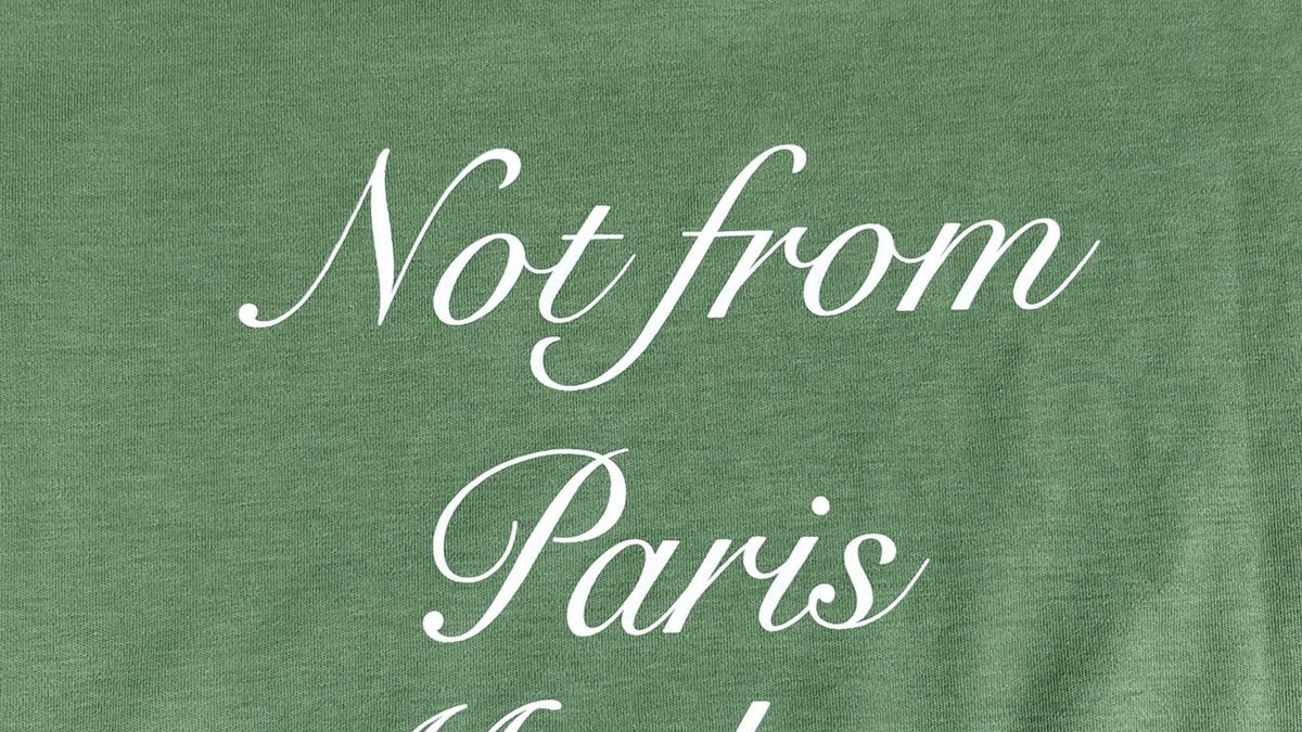 Détail d'un tee-shirt Drôle de Monsieur Calligraphy vert, l'écriture signature de la marque