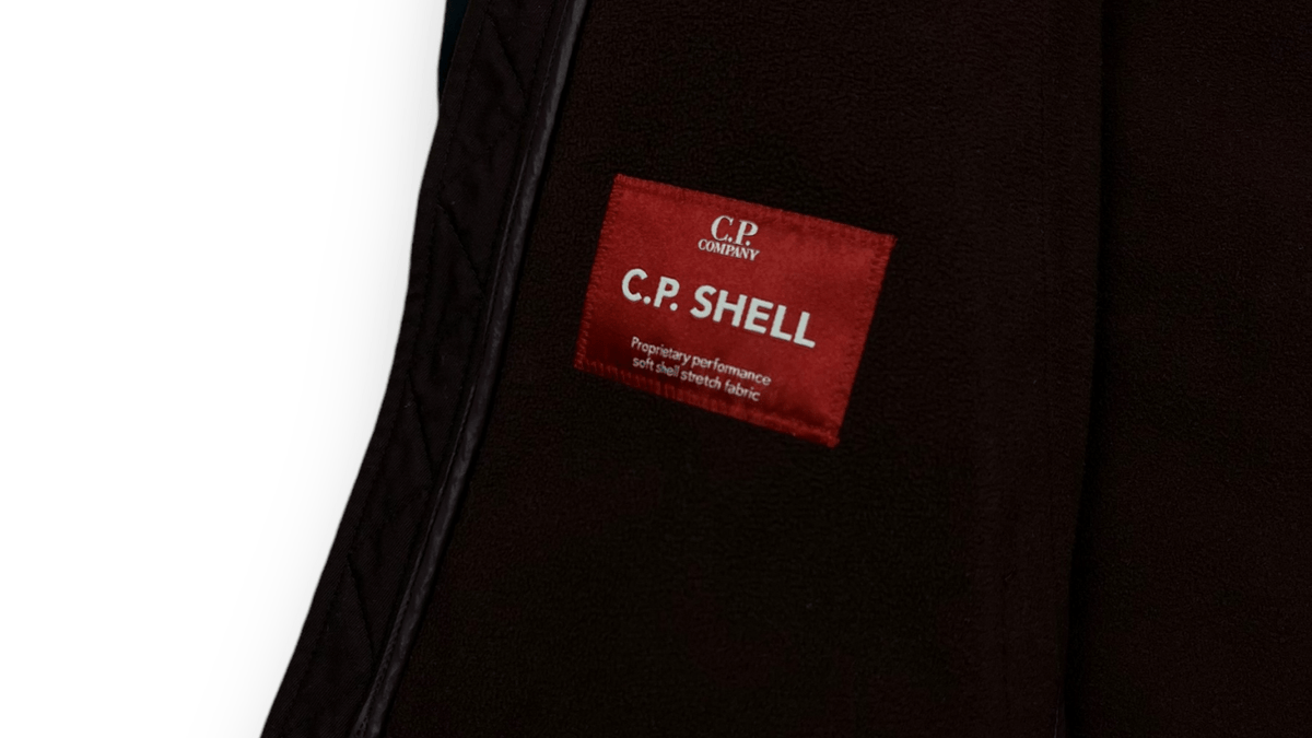Détail à lentille d'une veste C.P Company marine, pièce emblème de la culture casual