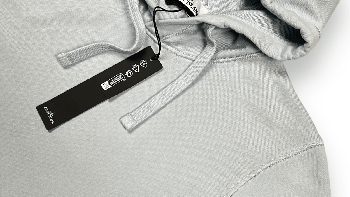 Détail d'un sweat Stone Island bleu ciel, pièce emblème de la culture casual