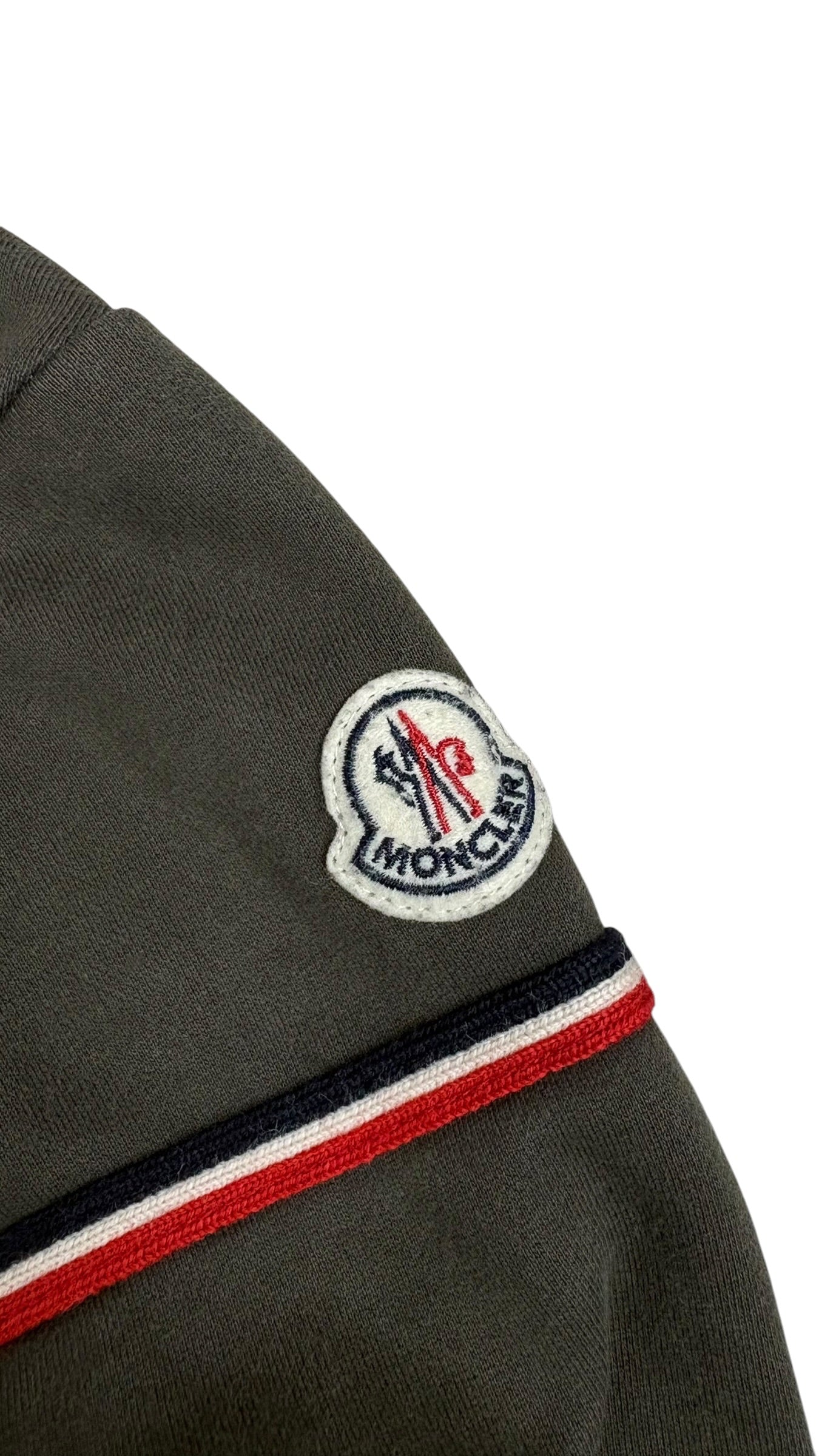 Gros plan de l'écusson Moncler cousu sur la manche du cardigan kaki, avec bande tricolore bleu-blanc-rouge