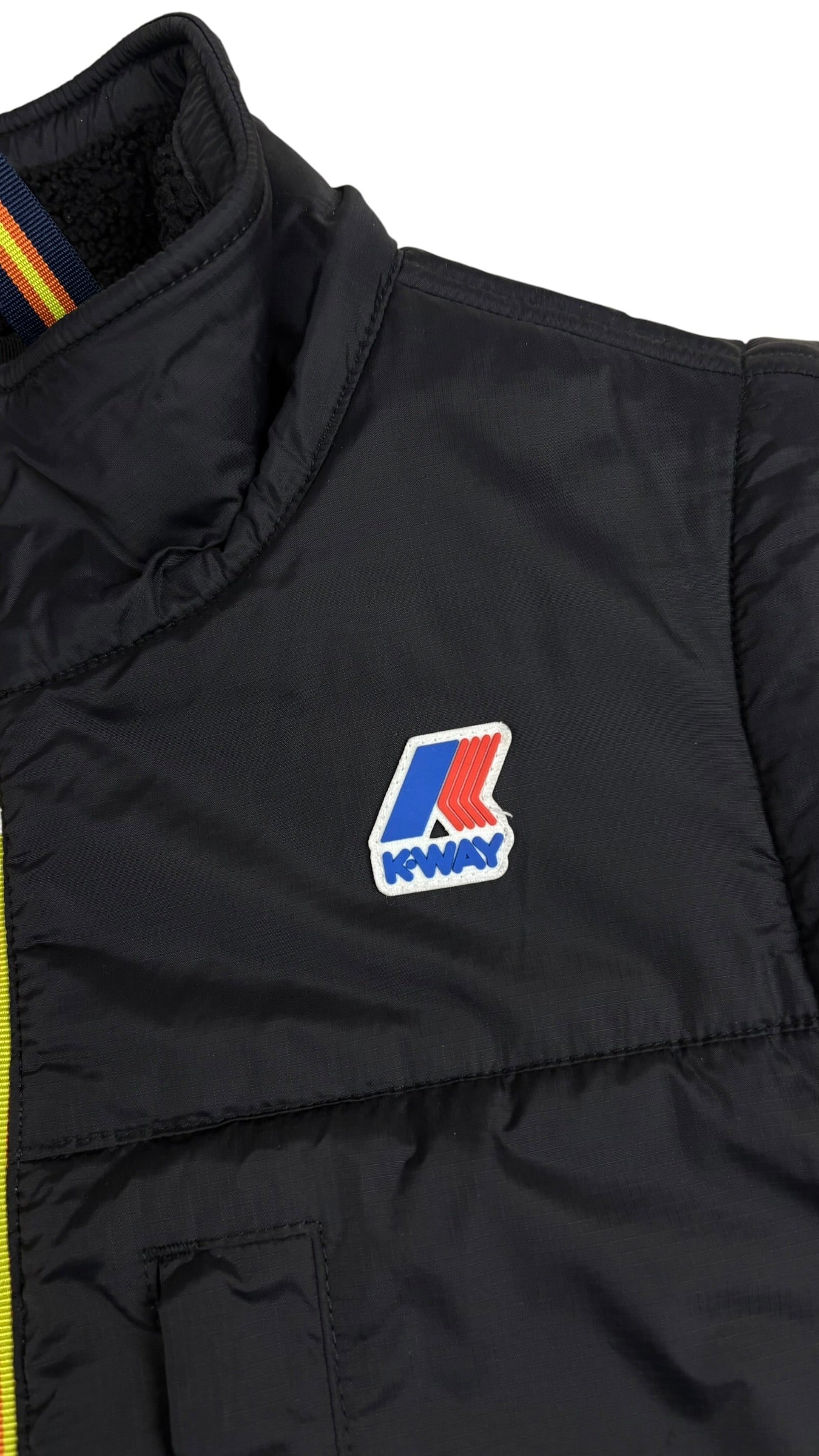 Detail du logo K-Way brode sur la poitrine du gilet noir et du col montant