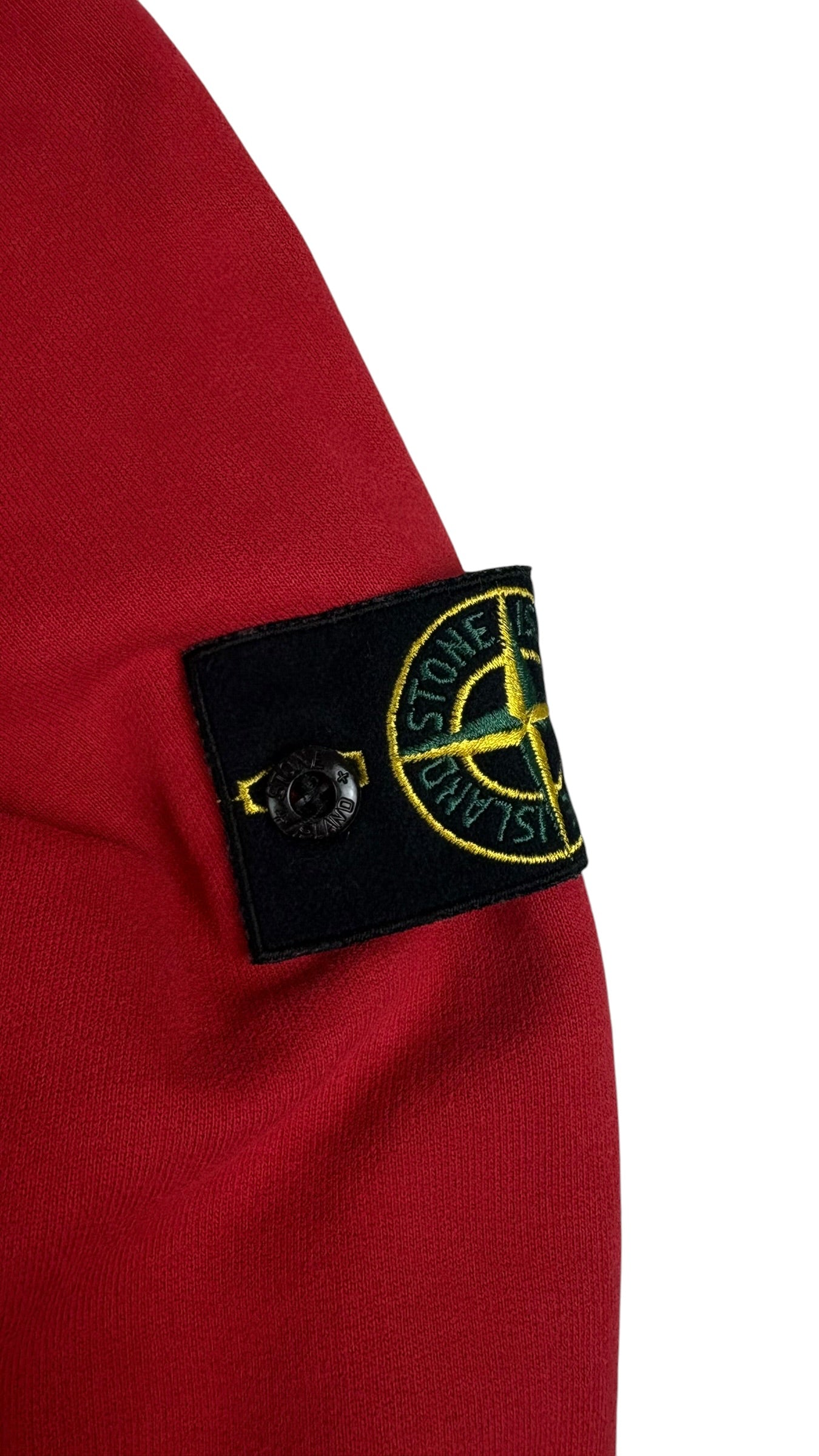 Gros plan du badge boussole Stone Island cousu sur la manche du hoodie rouge