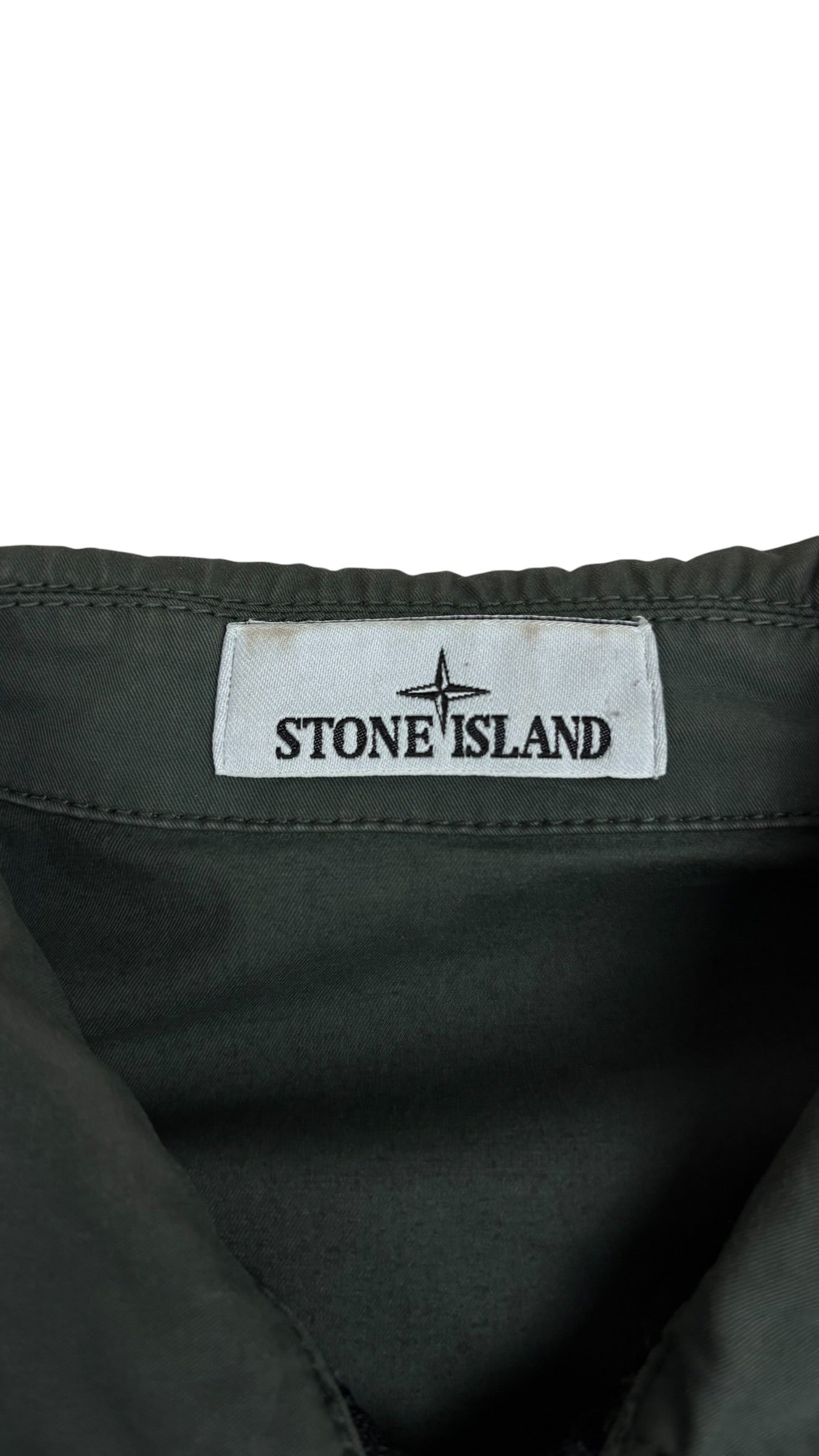 Gros plan sur l'écusson boussole Stone Island cousu sur la manche de la surchemise kaki, autre angle, vue détail