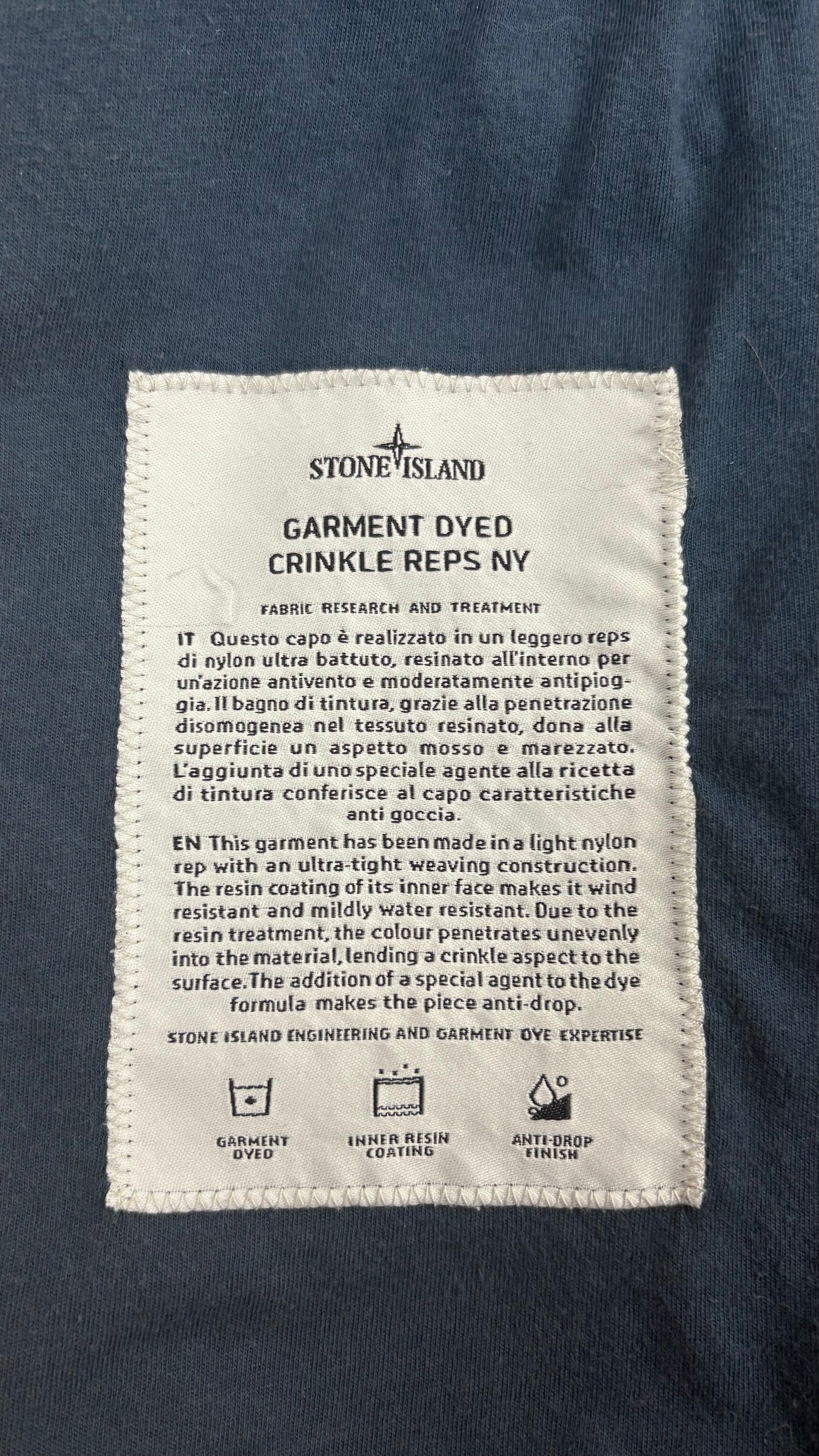Étiquette technique Stone Island Garment Dyed Crinkle Reps NY décrivant le tissu nylon teint en pièce, la finition déperlante et le revêtement résine, vue détail