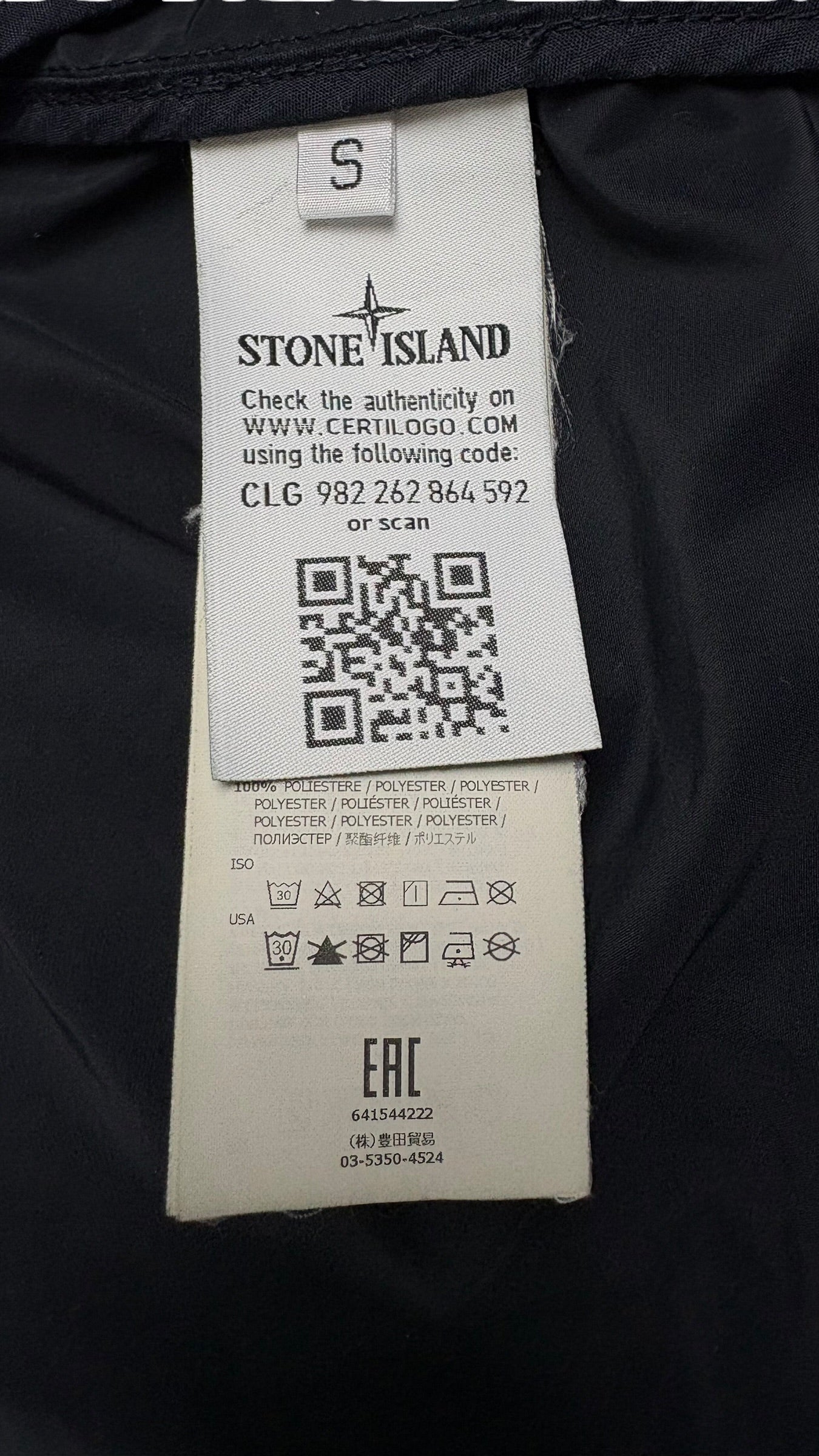 Étiquette intérieure de la veste Stone Island indiquant la taille S, la composition en polyester, les instructions de lavage et un QR code Certilogo d'authenticité, vue détail
